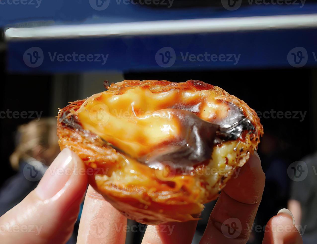 schließen oben ein Hand halten ein traditionell pasteis de nata traditionell portugiesisch Gebäck Küche Ei Torte mit cremig Füllung, Pudding foto