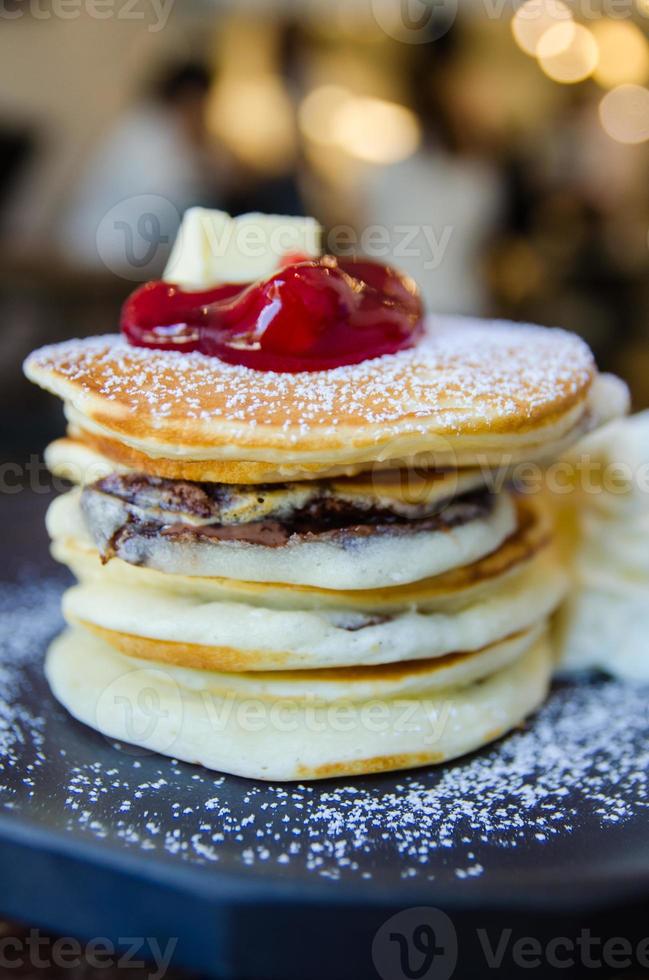 Stapel von Pfannkuchen mit Erdbeere auf oben auf schwarz Teller foto