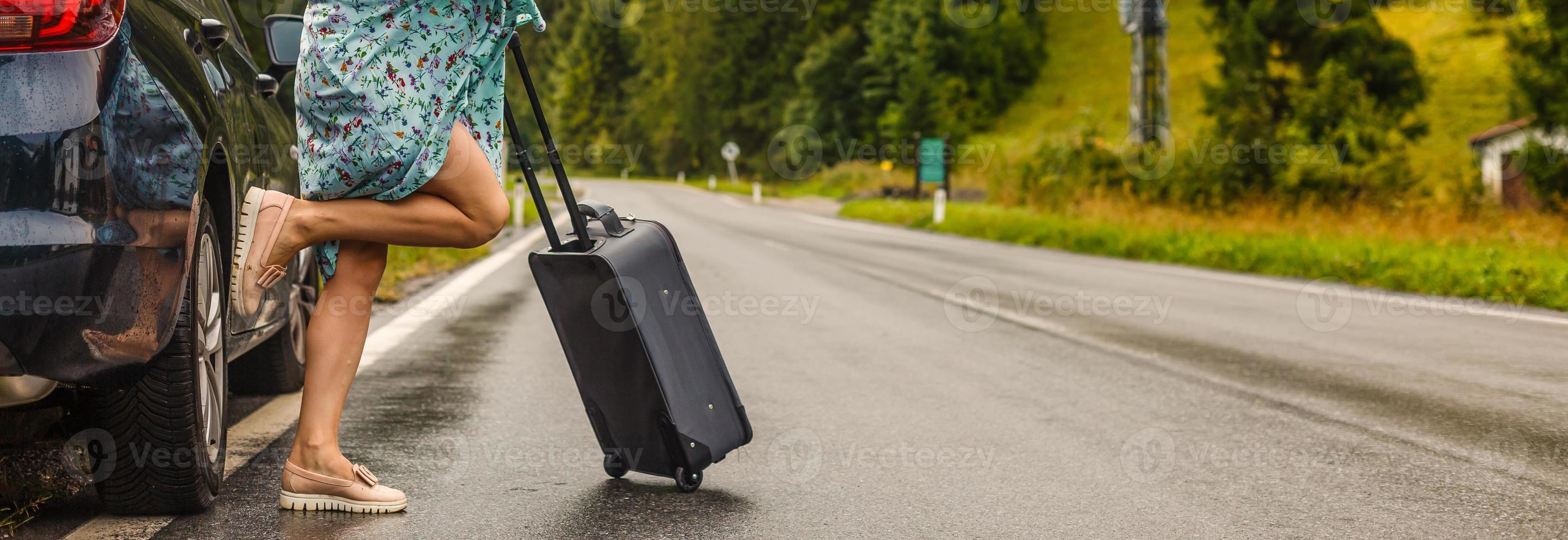 abgeschnitten Bild von Frau Tragen auf Rädern Tasche während ihr freunde warten in der Nähe von Reise Bus beim städtisch Straße foto