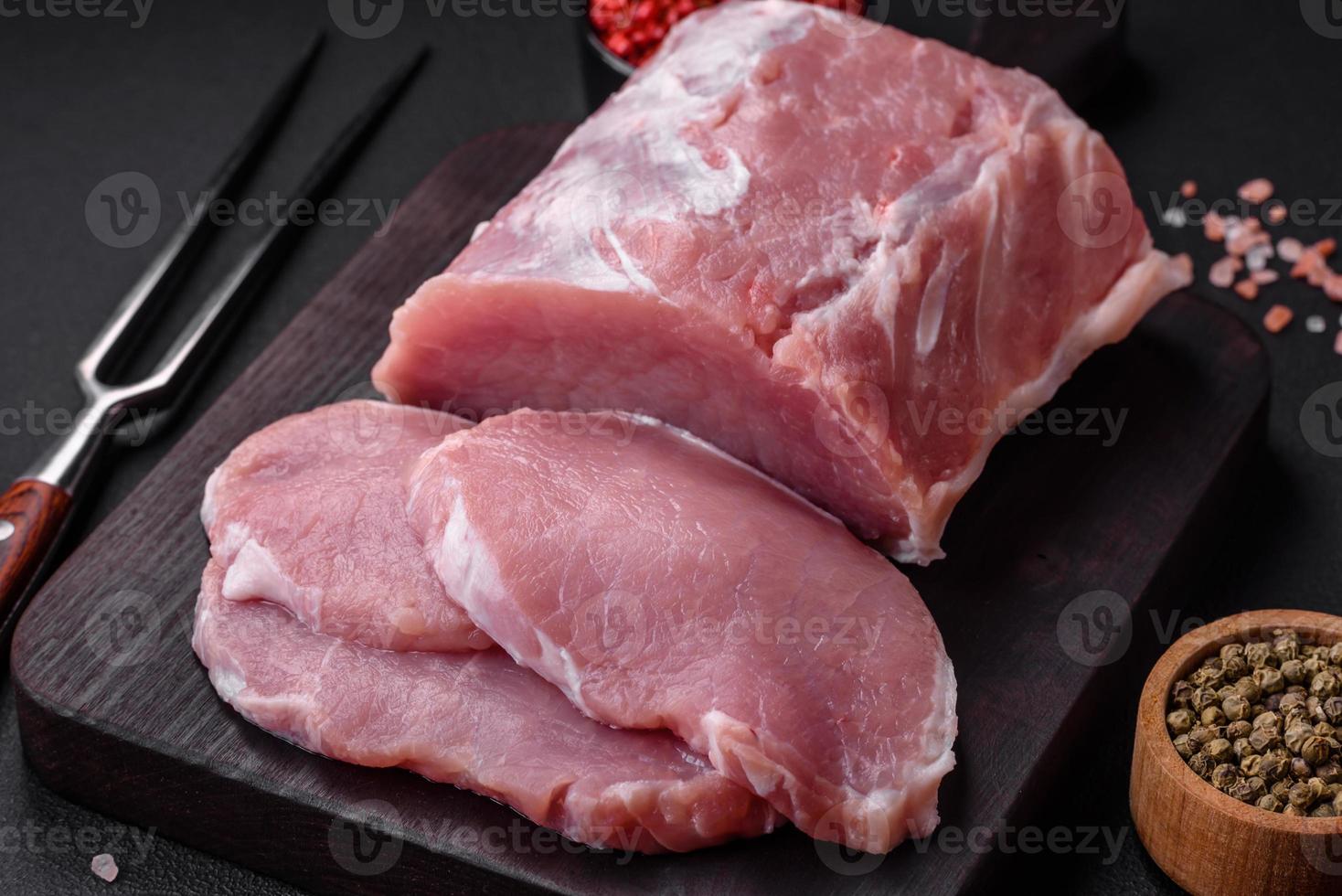 frisch saftig Schweinefleisch auf ein hölzern Schneiden Tafel mit Gewürze und Salz- foto