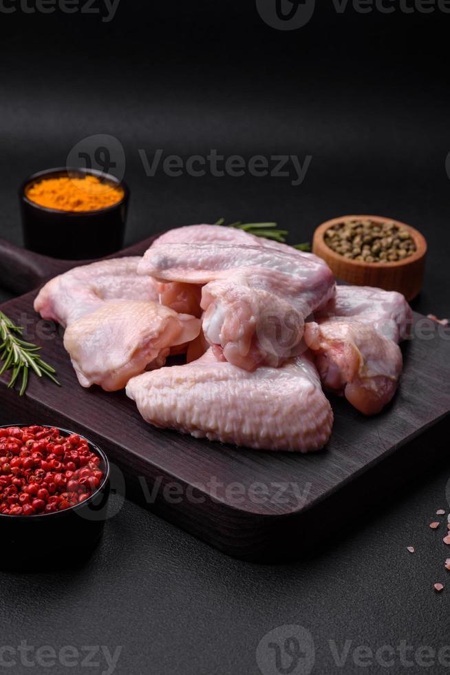 roh Hähnchen Flügel mit Salz, Gewürze und Kräuter auf ein hölzern Schneiden Tafel foto