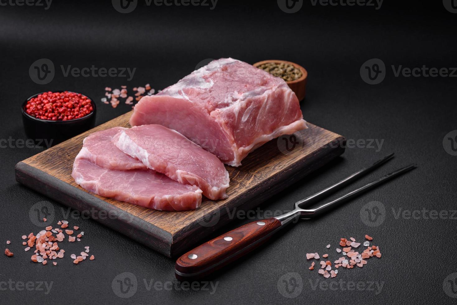 frisch saftig Schweinefleisch auf ein hölzern Schneiden Tafel mit Gewürze und Salz- foto