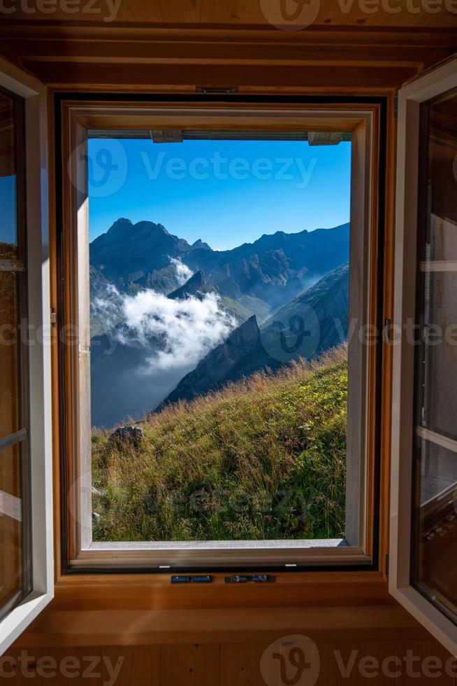ein Berg Landschaft fotografiert von ein Haus, das Fenster Formen das Rahmen von das Bild foto
