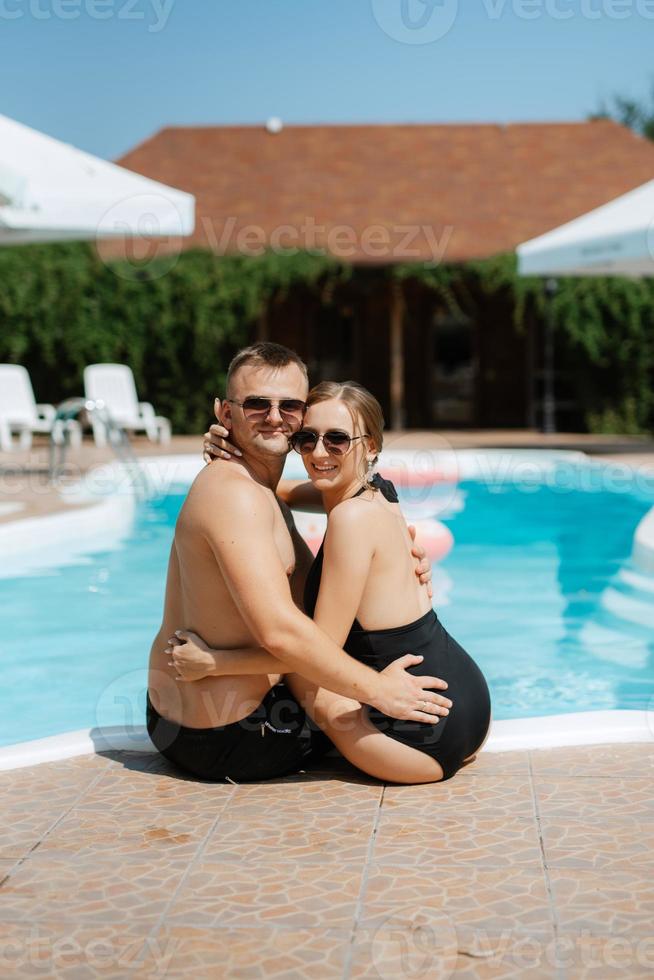 Kerl und ein Mädchen im Baden Anzüge sind entspannend, in der Nähe von das Blau Schwimmbad foto