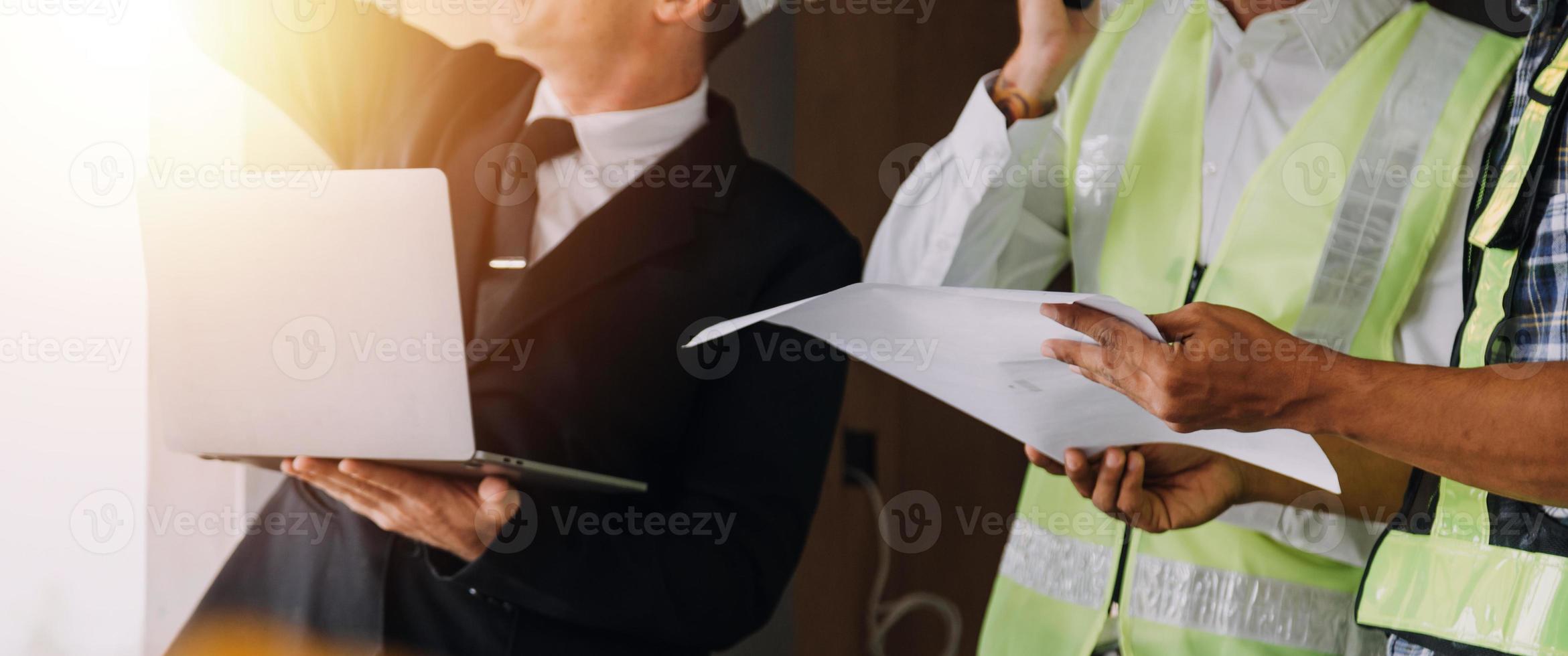 zwei Geschäftsmann Baustelleningenieur. Engineering-Objekte am Arbeitsplatz mit Partnern, die im Hintergrund interagieren foto