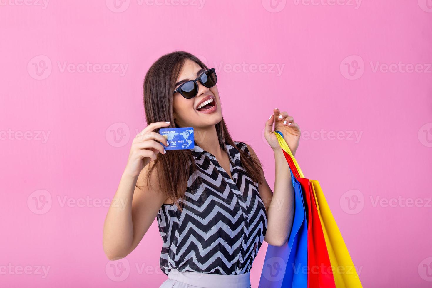 schön jung Frau mit Einkaufen Taschen halten ihr Anerkennung Karte auf Rosa hintergrund.shopaholic Einkaufen Mode. foto