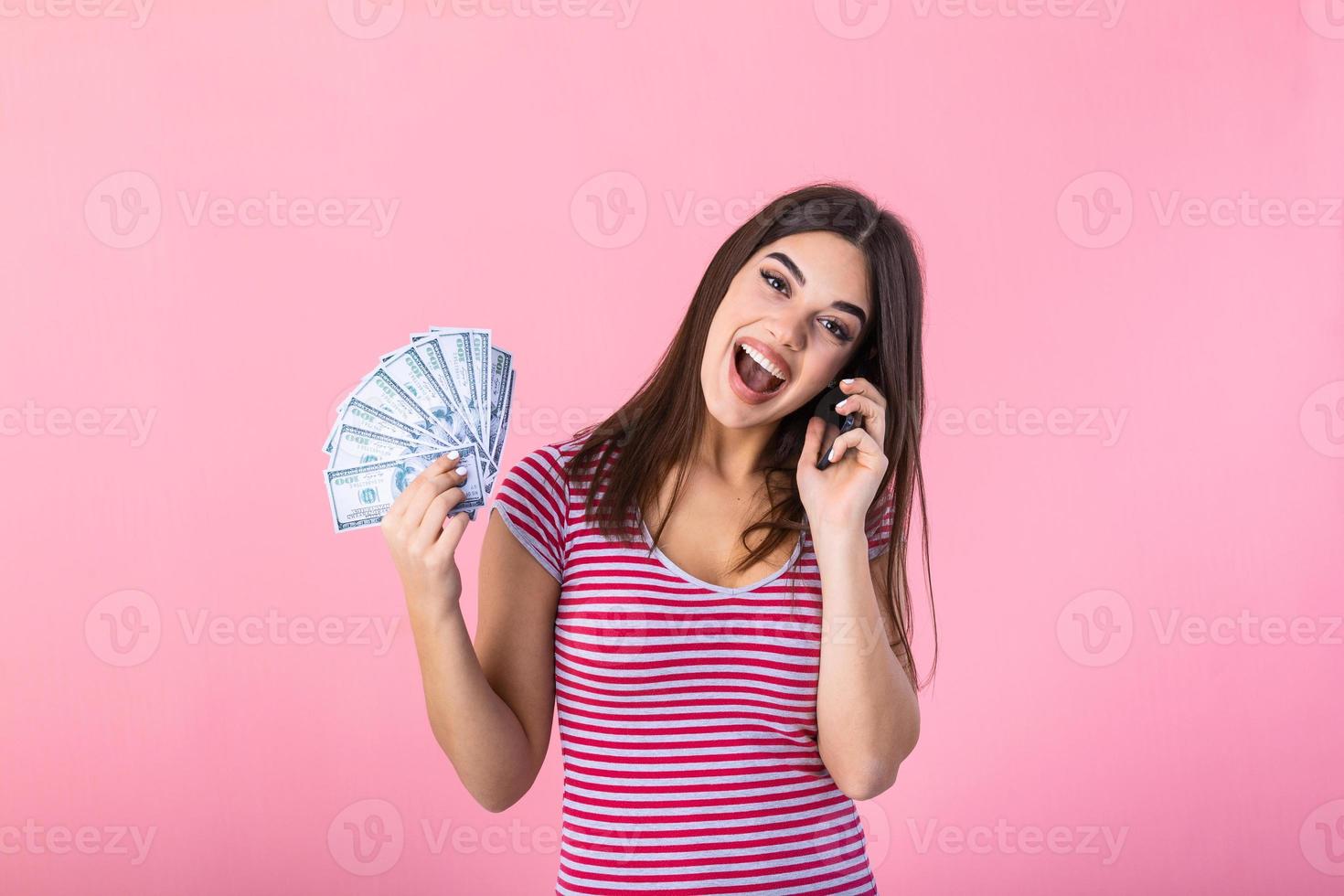 Bild einer schockierten, überraschten, schreienden jungen, hübschen Frau, die isoliert über rosafarbenem Wandhintergrund mit einem Handy posiert, das Geld hält. foto