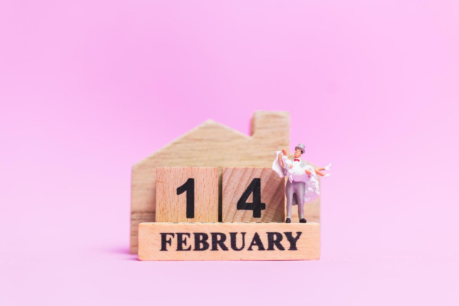 Miniaturhochzeit eines Braut- und Bräutigampaares auf einem rosa Hintergrund, Valentinstagkonzept foto