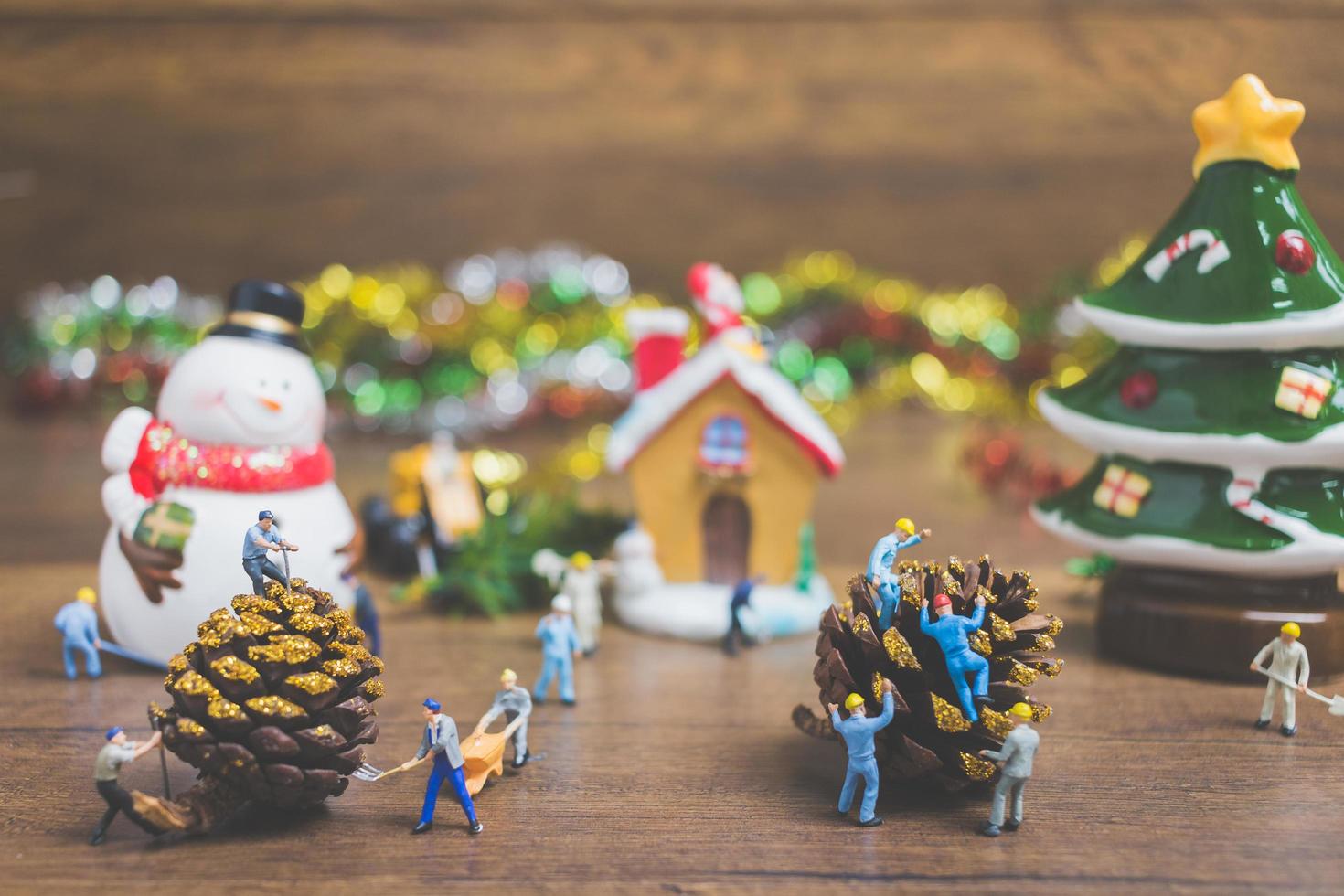 Miniaturmenschen, die Weihnachtsdekorationen auf einem hölzernen Hintergrund schaffen foto