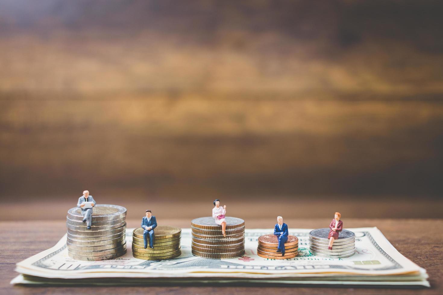Miniaturgeschäftsleute auf Geld auf einem hölzernen Hintergrund foto