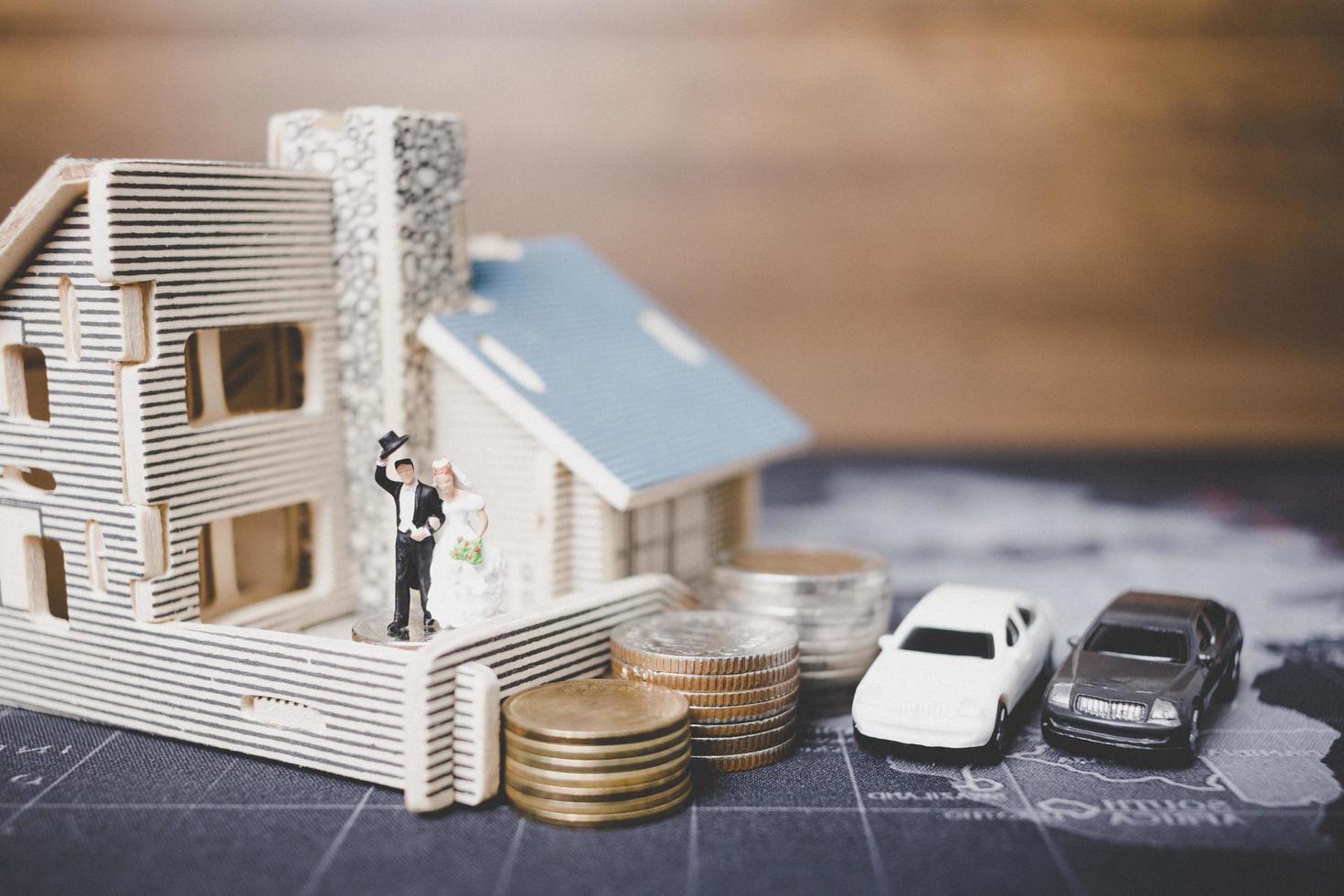Miniatur Braut und Bräutigam mit Münzen vor einem Haus, erfolgreiches Familienkonzept foto