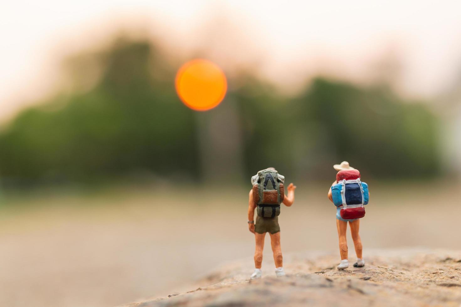 Miniaturreisende mit Rucksäcken auf einem Felsen-, Reise- und Abenteuerkonzept foto