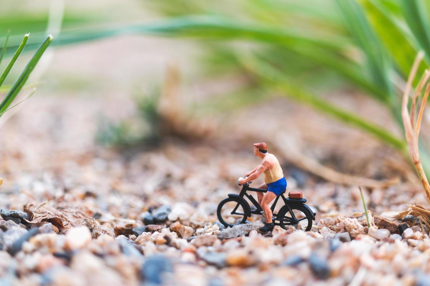 Miniaturreisender, der Fahrrad fährt und das Weltkonzept erkundet foto