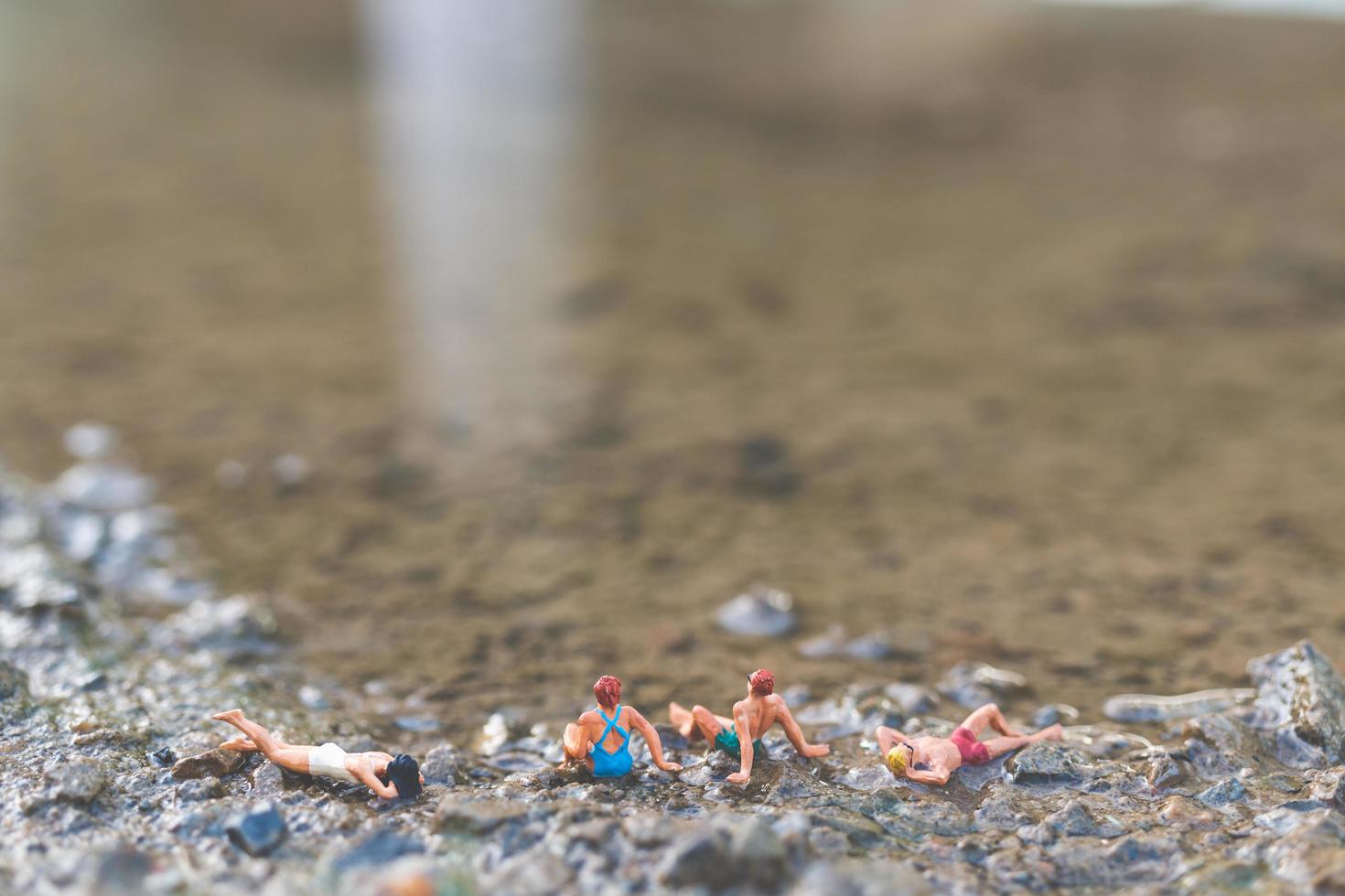 Miniaturmenschen, die Badeanzüge tragen, die auf einem Strand entspannen, Sommerkonzept foto