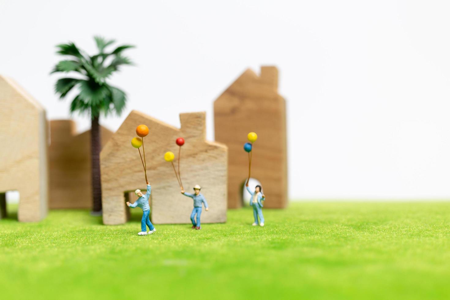 Miniaturfamilie, die in einem Feld mit Luftballons geht, glückliches Familienzeitkonzept foto