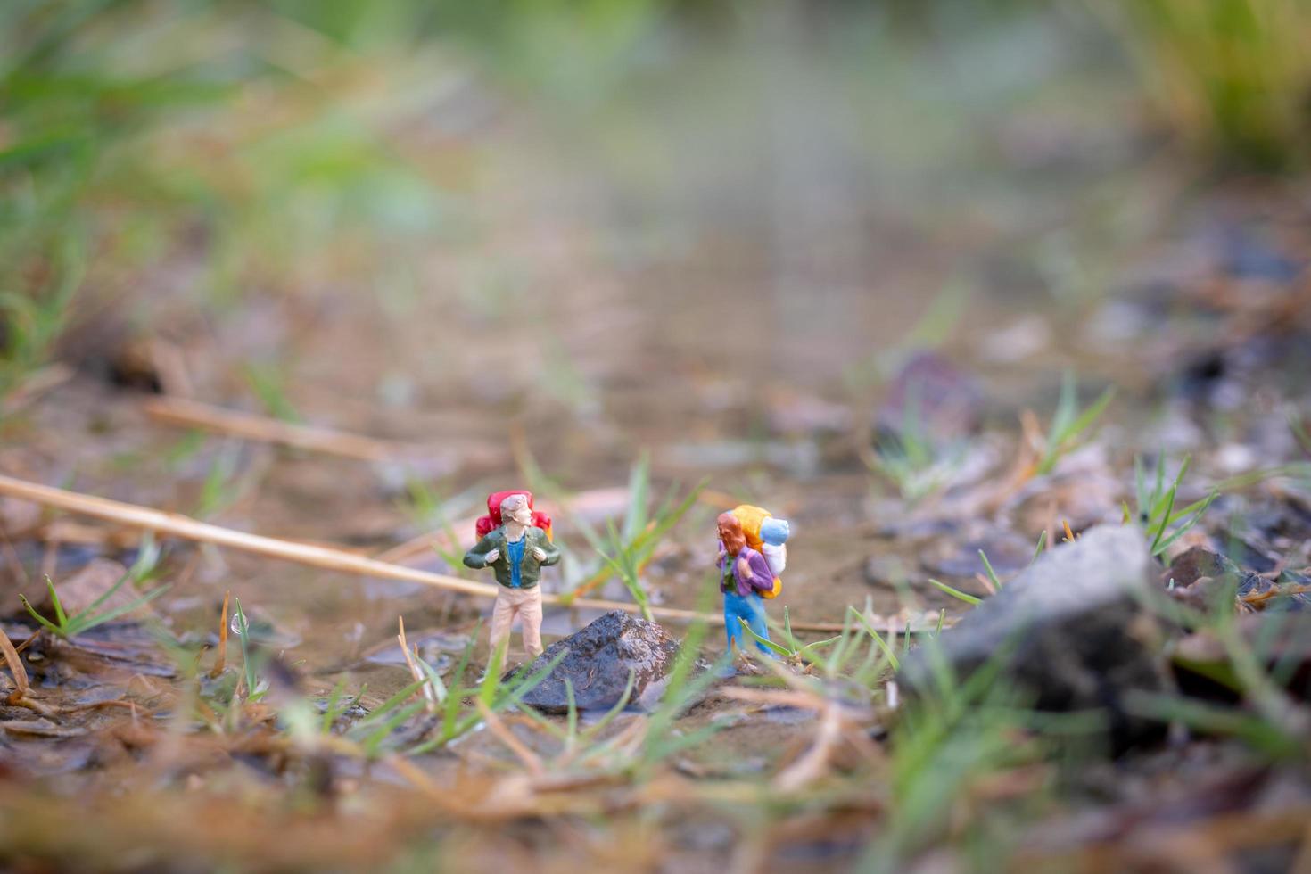 Miniaturreisender mit Rucksäcken auf dem Feld, Reise- und Abenteuerkonzept foto