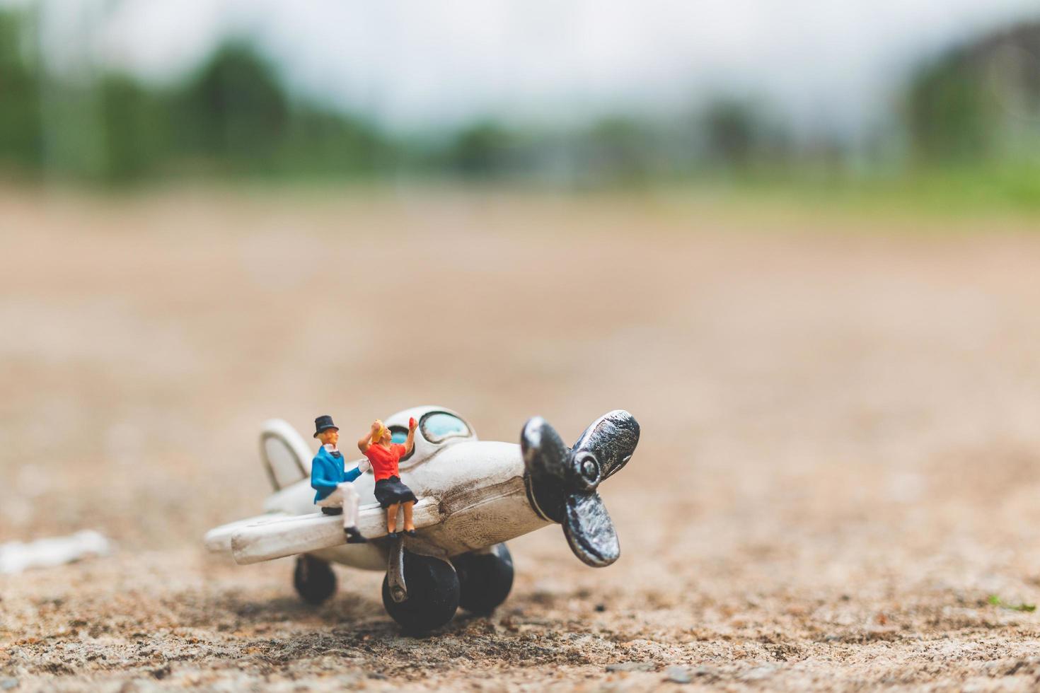 Miniaturpaar, das in einem Flugzeug sitzt und das Weltkonzept erforscht foto