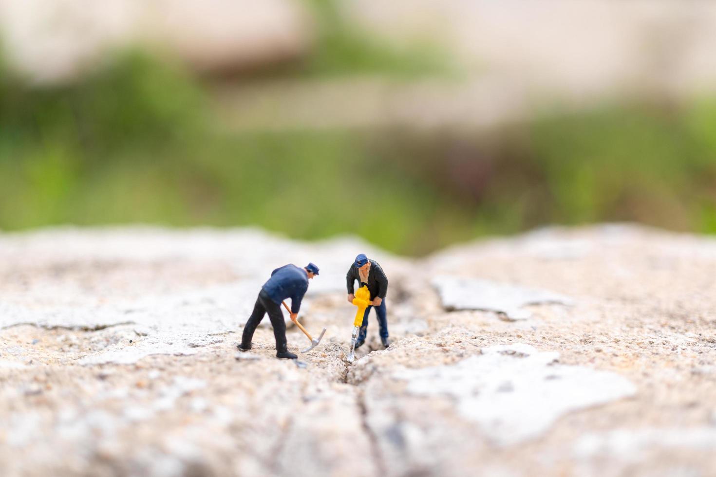 Miniaturarbeiter arbeiten an Beton mit Rissen, Teamwork-Konzept foto