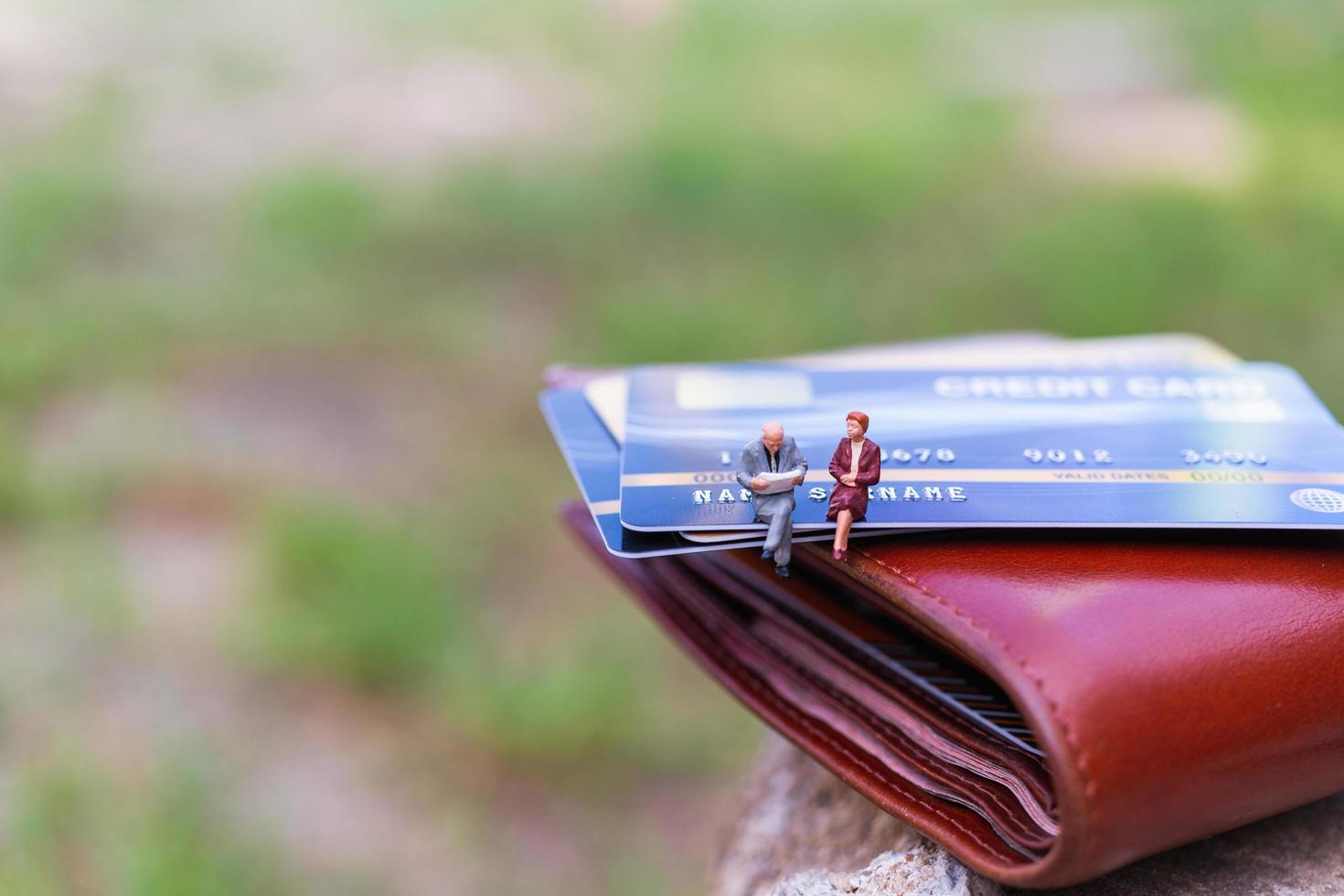 Miniatur-Geschäftsleute, die auf einer Kreditkarte sitzen, Geschäfts- und Finanzkonzepte foto