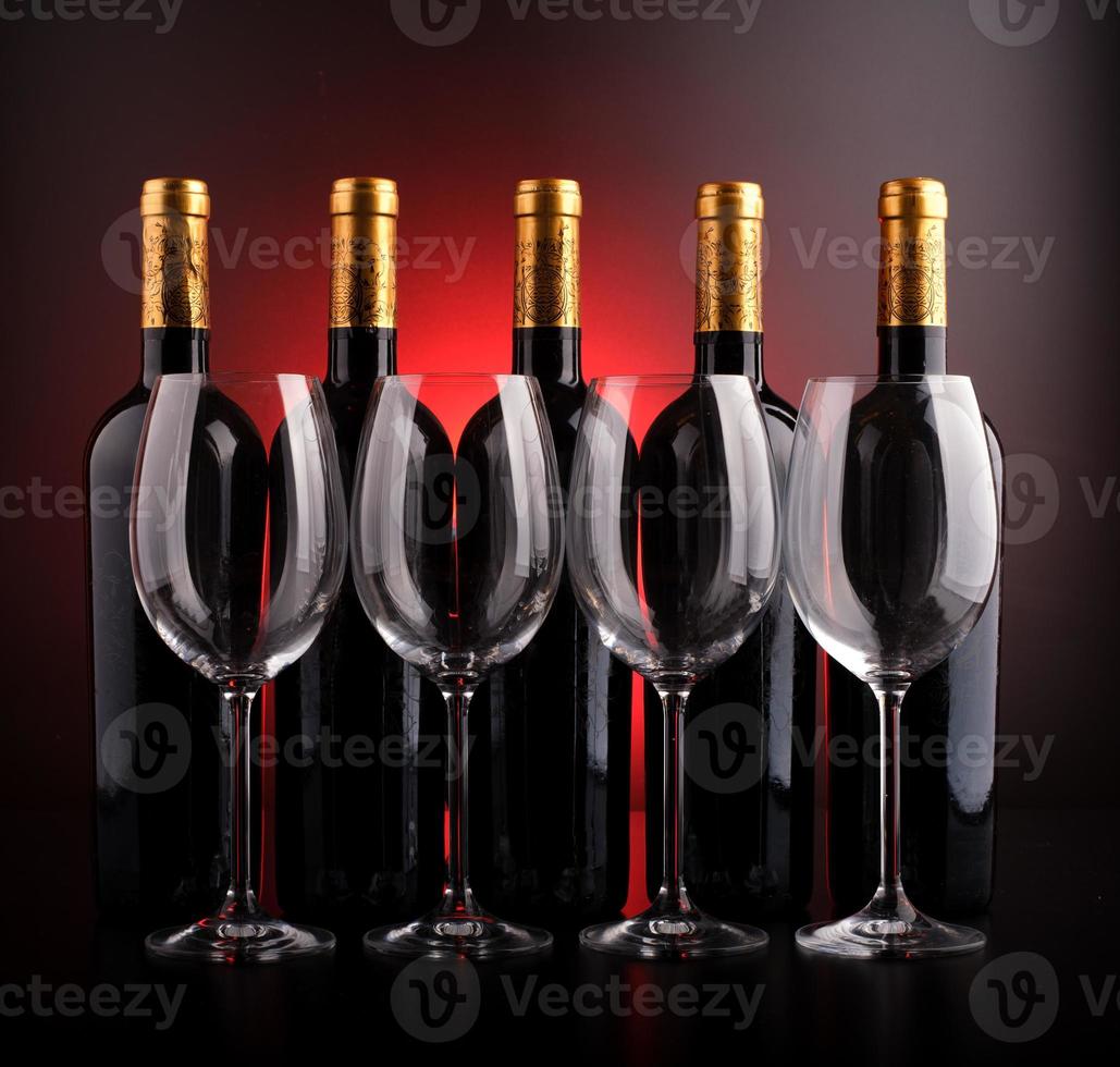Weinflaschen und Gläser mit schwarzem und rotem Hintergrund foto