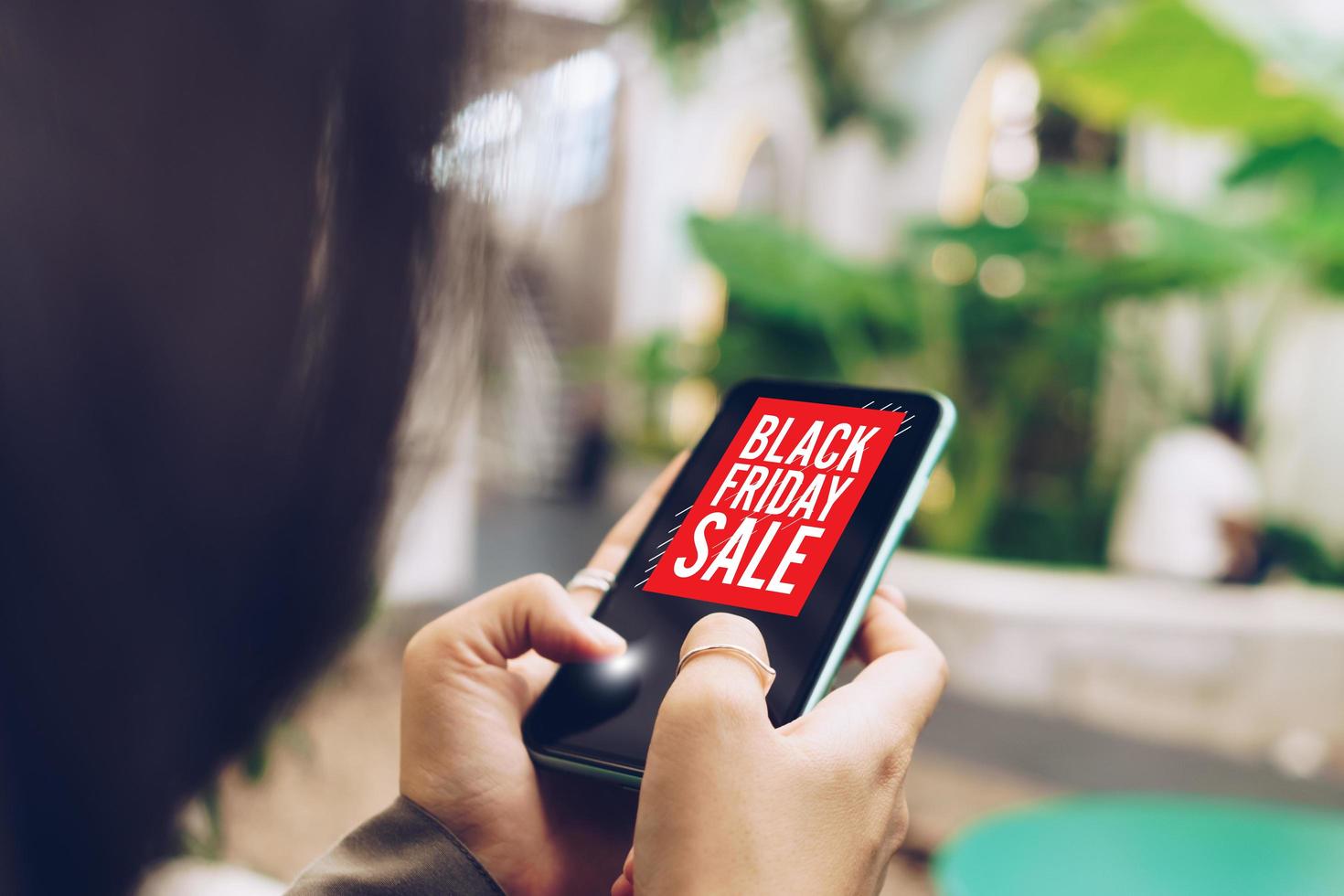 Frau, die ein Smartphone benutzt, macht Online-Verkauf am schwarzen Freitag-Verkauf foto