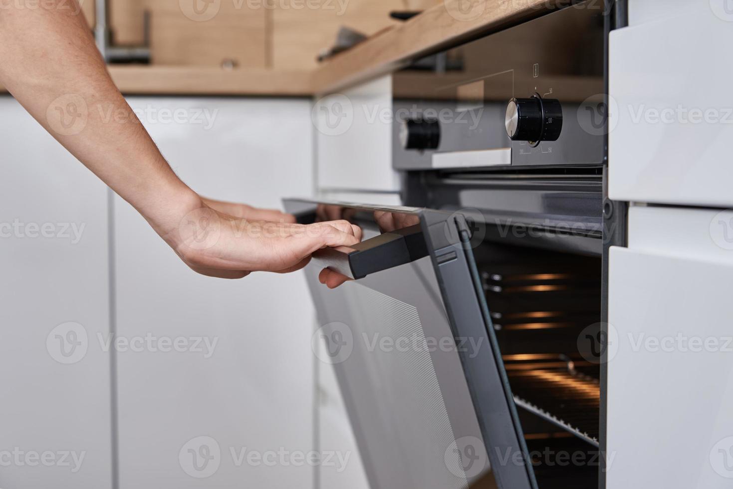 Frau öffnet elektrische Ofentür foto