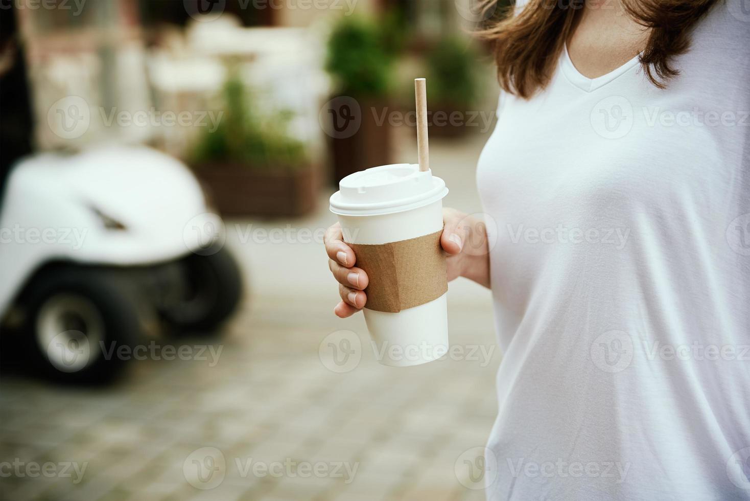 frau hält papierkaffeetasse an der stadtstraße foto