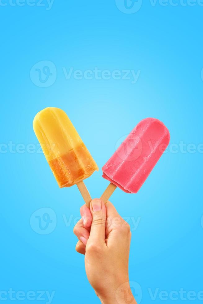 zweifarbige Eis am Stiel in Frauenhänden auf blauem Hintergrund foto