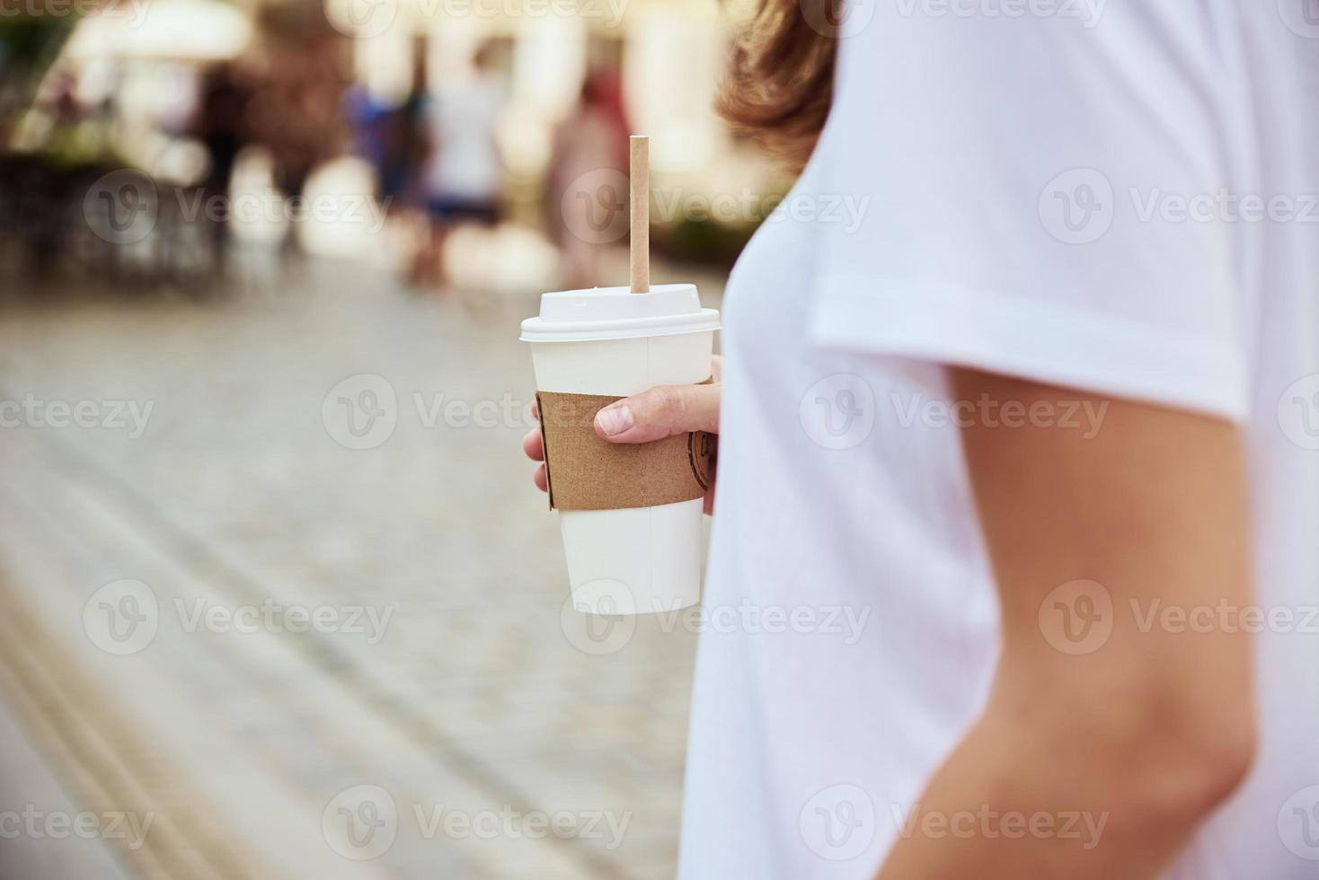 frau hält papierkaffeetasse an der stadtstraße foto