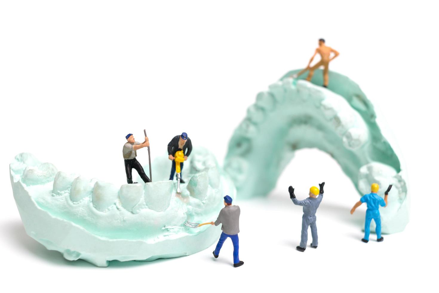 Miniaturarbeiter, die falsche Zähne füllen und sie in eine Prothese aus Gips setzen, Laborkonzept für Zahnprothesen foto