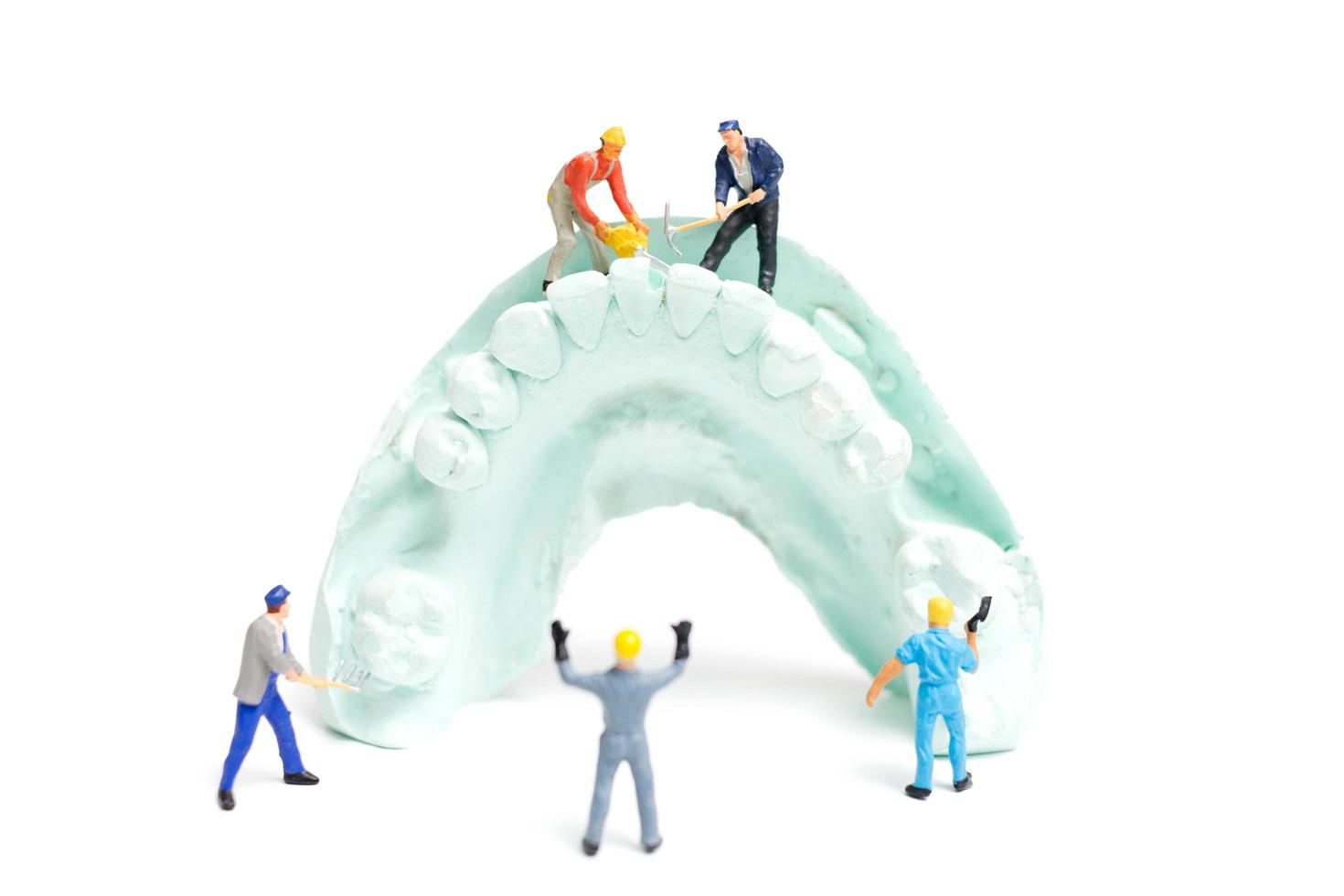 Miniaturarbeiter, die falsche Zähne füllen und sie in eine Prothese aus Gips setzen, Laborkonzept für Zahnprothesen foto