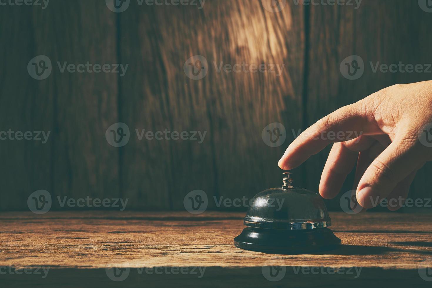 Glockendienst mit einer Hand auf einem hölzernen Hintergrund foto