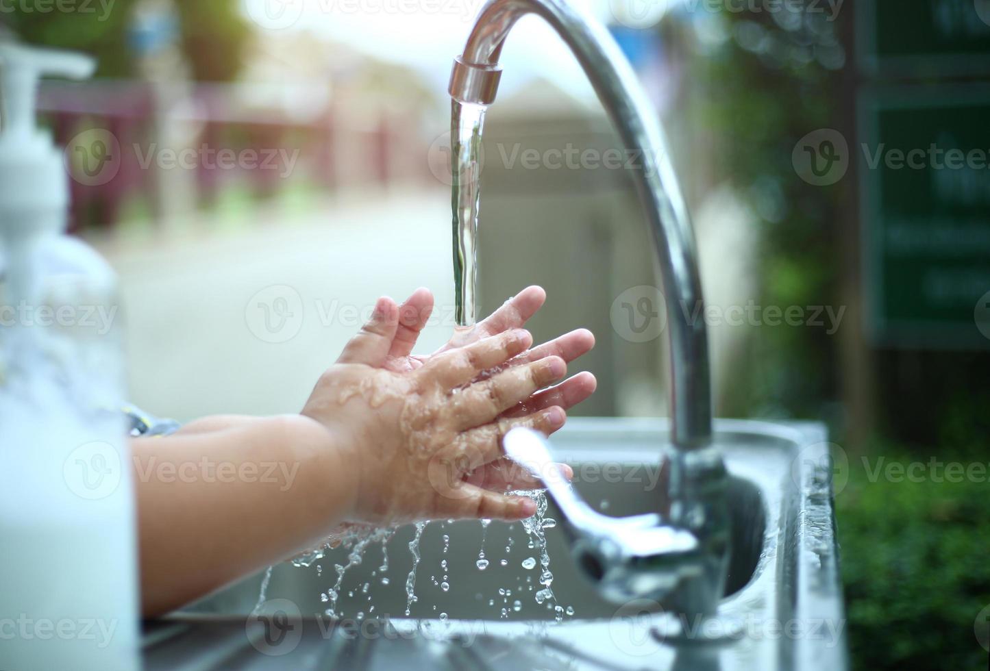 Kind, das seine Hände mit Seife im Freien, Hygiene- und Reinigungskonzept wäscht foto