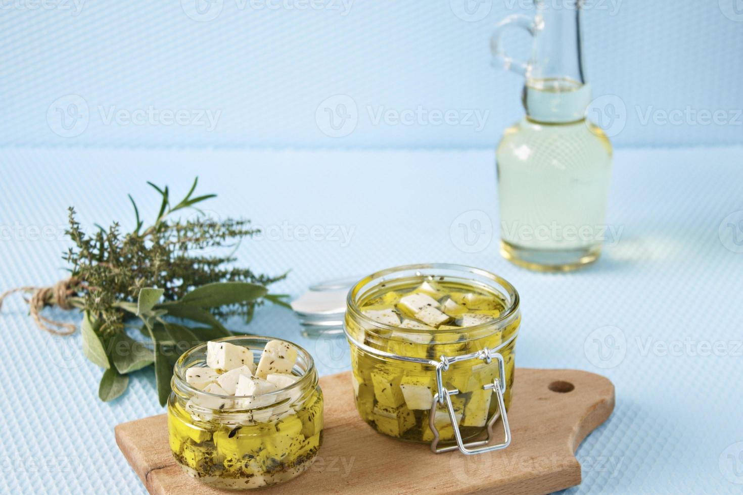 marinierter Feta in einem Glas und Gewürzen vor blauem Hintergrund foto