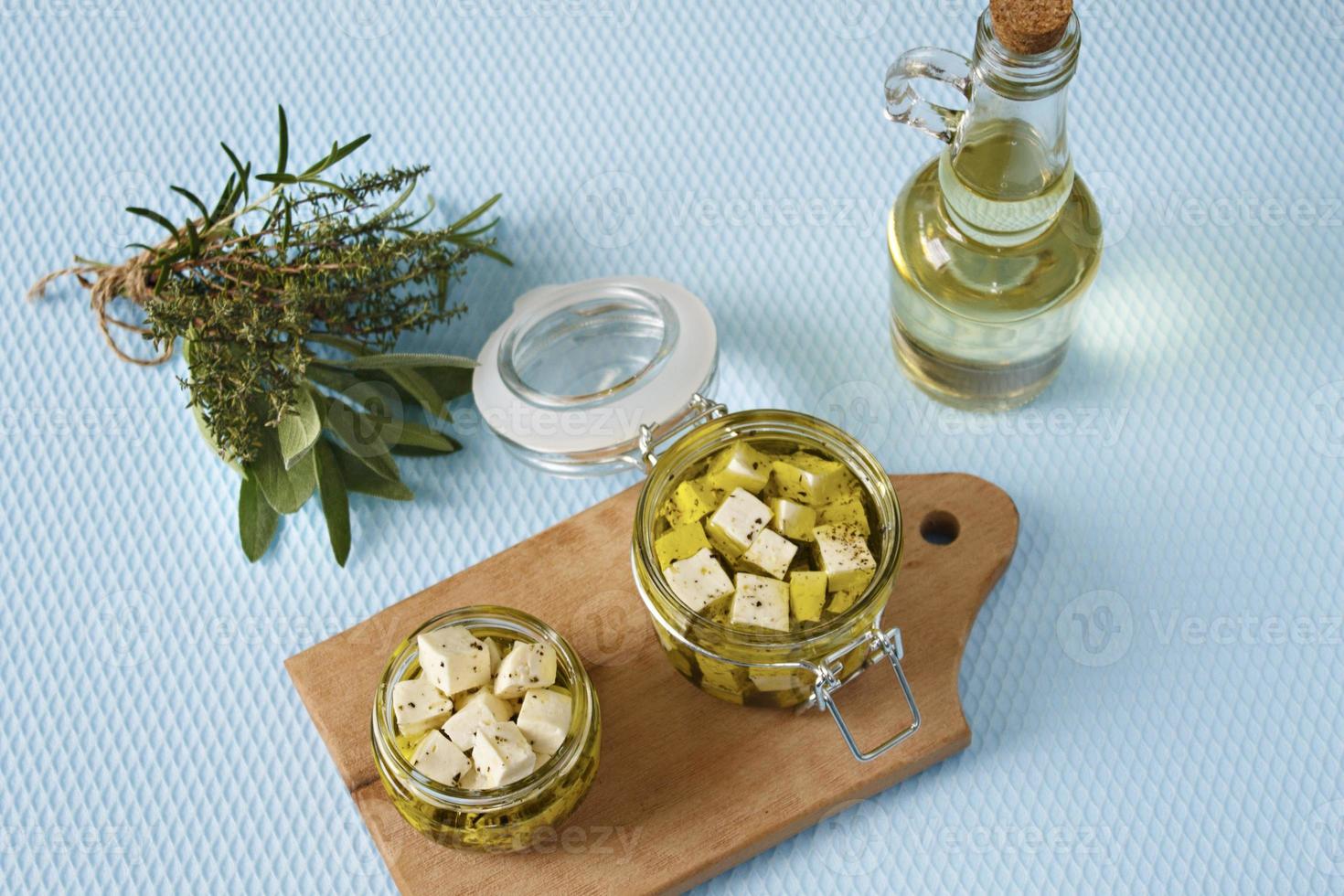 marinierter Feta in einem Glas und Gewürzen vor blauem Hintergrund foto