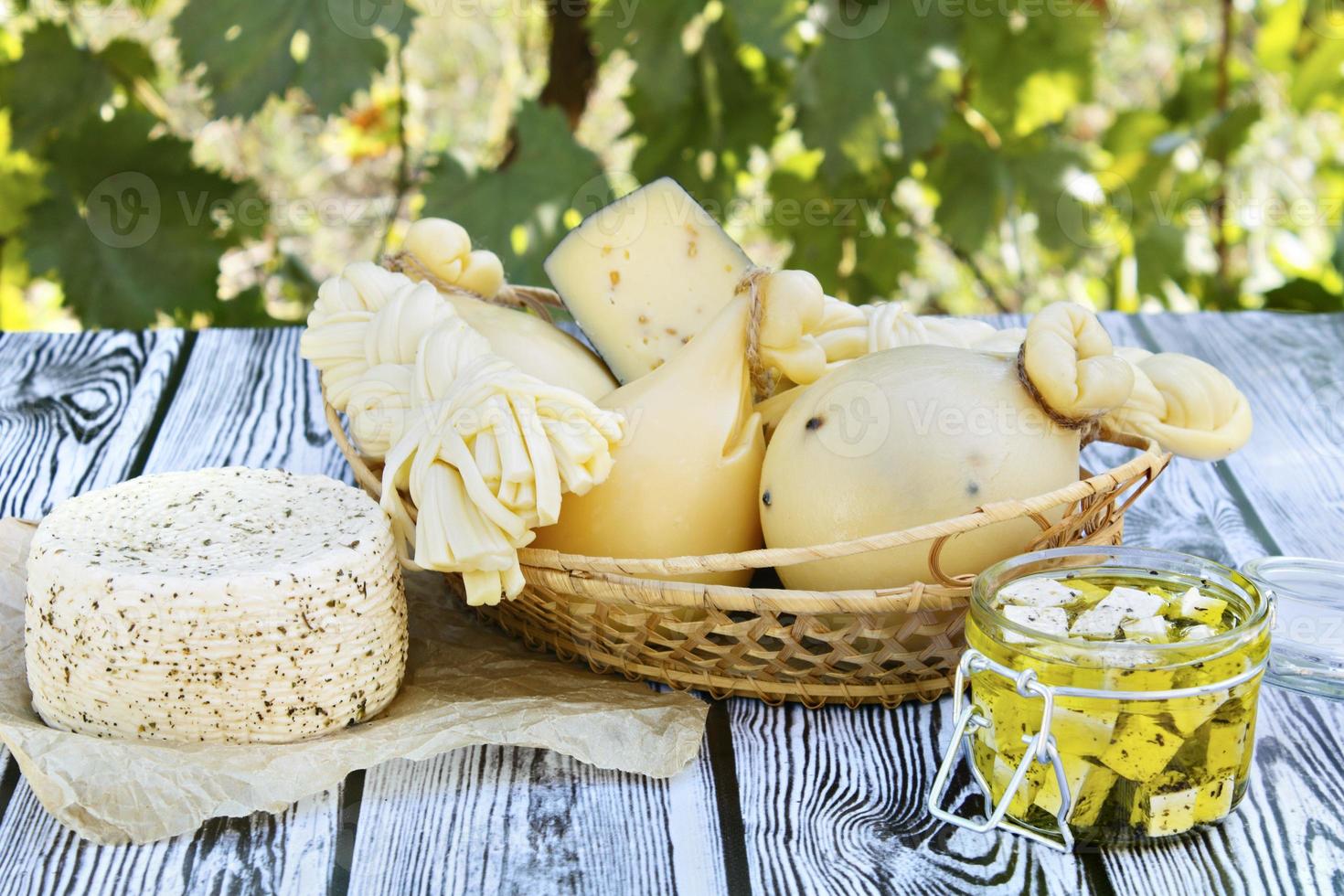 verschiedene Arten von Käse auf einem hölzernen Hintergrund vor dem Hintergrund des grünen Laubs foto