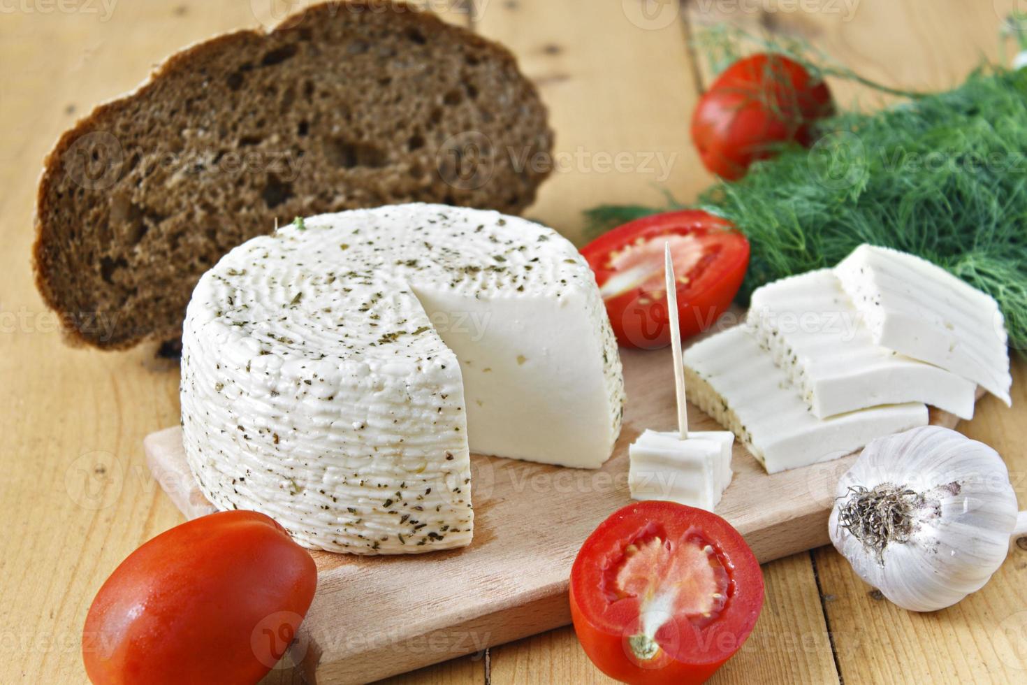 weißer Käse, Brot, Tomaten und Knoblauch auf einem hölzernen Hintergrund foto