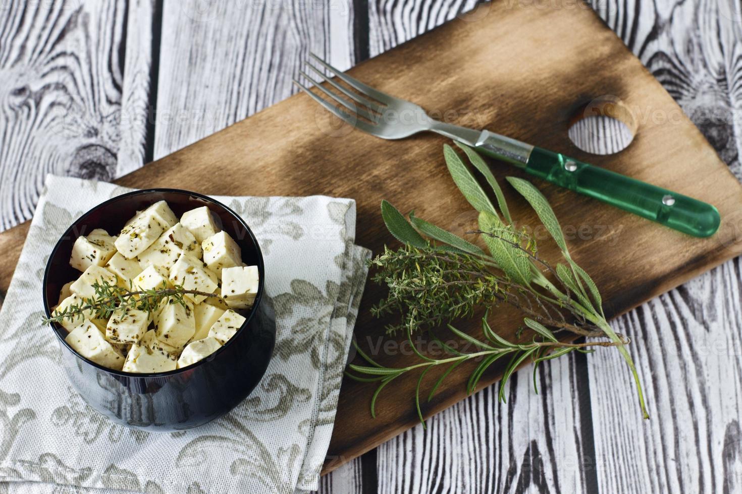 marinierter Feta in einem Teller auf einem Holzbrett auf einem hölzernen Hintergrund foto