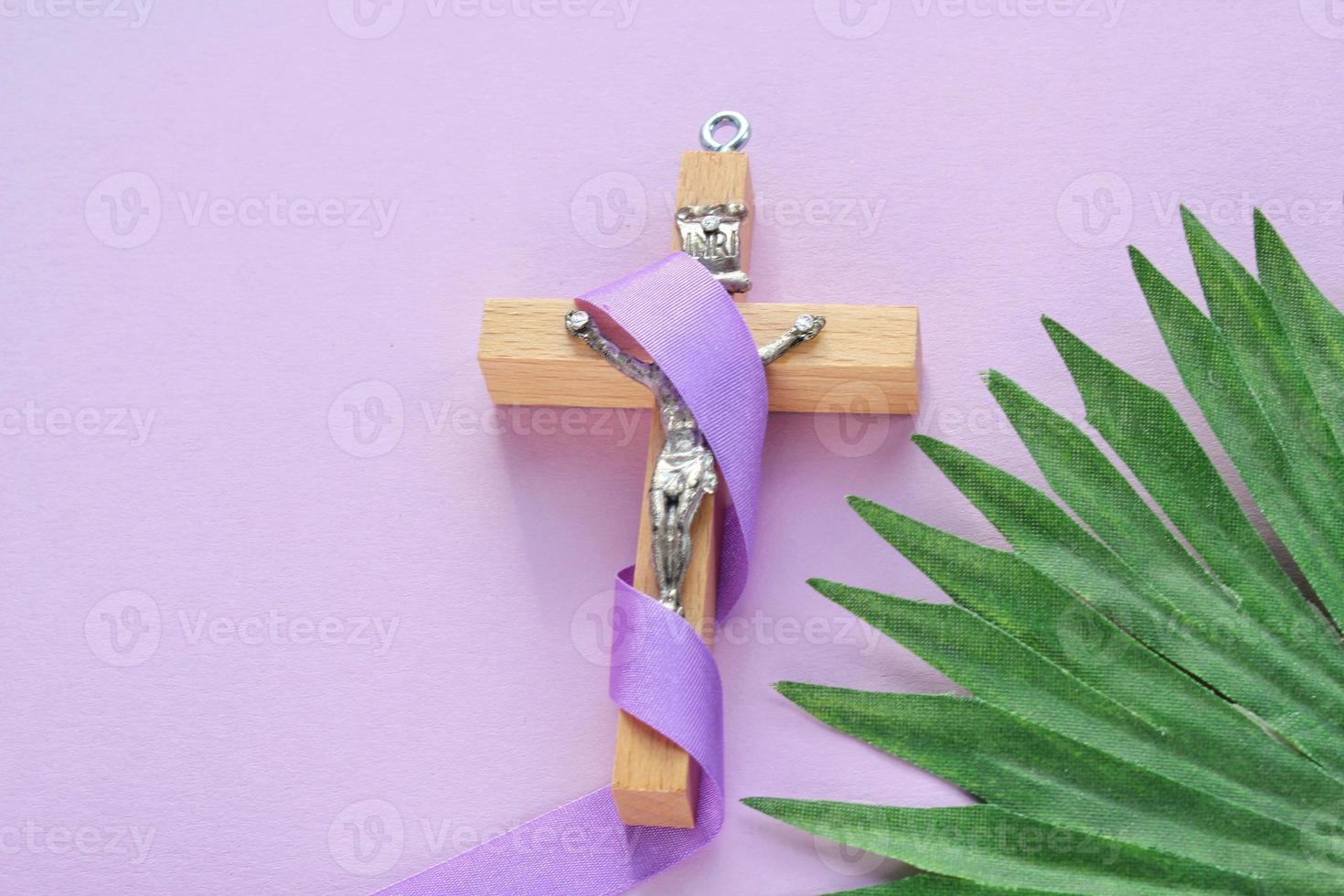 Christian religiös hölzern Kreuz Kruzifix mit violett Band auf lila Hintergrund. katholisch Religion Symbol. gut Freitag, Fastenzeit Jahreszeit, Palme Sonntag, Asche Mittwoch und heilig Woche Konzept foto