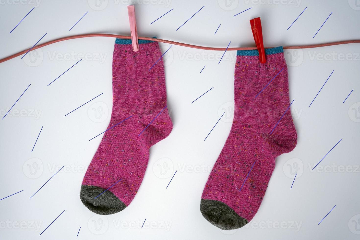 Damen Purpur Socken hängen und trocken auf ein Wäscheleine während das Regen. Absurdität und Humor foto