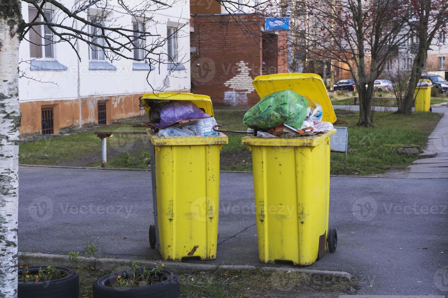 Gelb Behälter mit Haushalt Müll im das Hof von ein Wohnung Gebäude foto