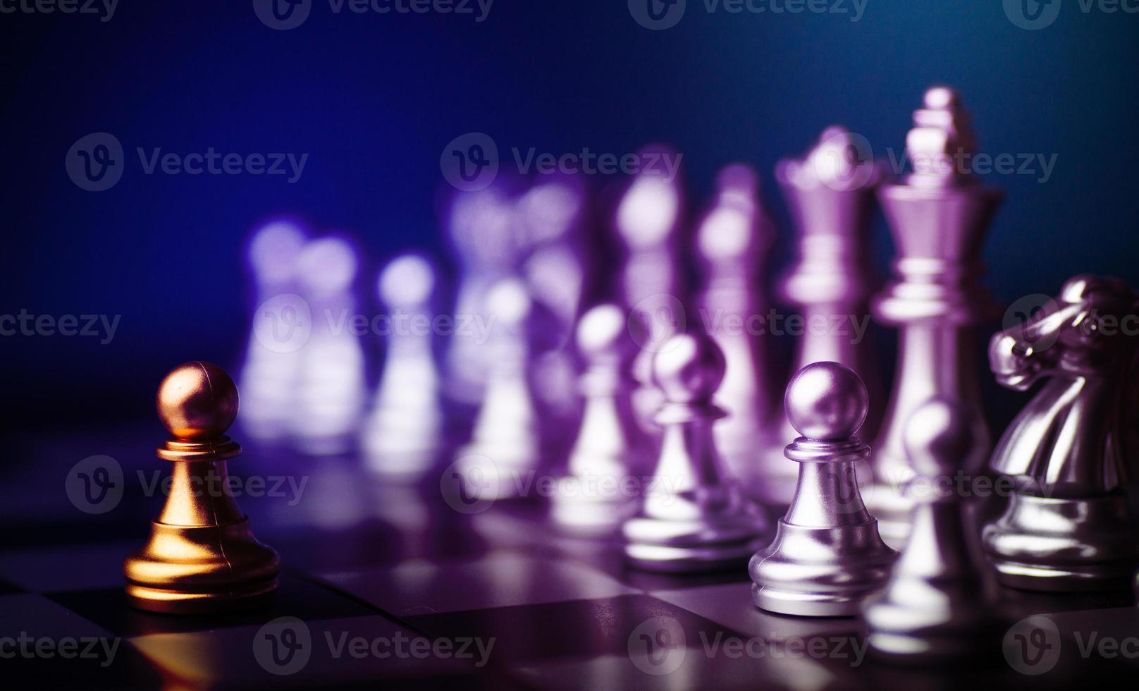 goldene Bauernschachfigur, die unter anderen silbernen Schachfiguren auf Schachbrett steht foto