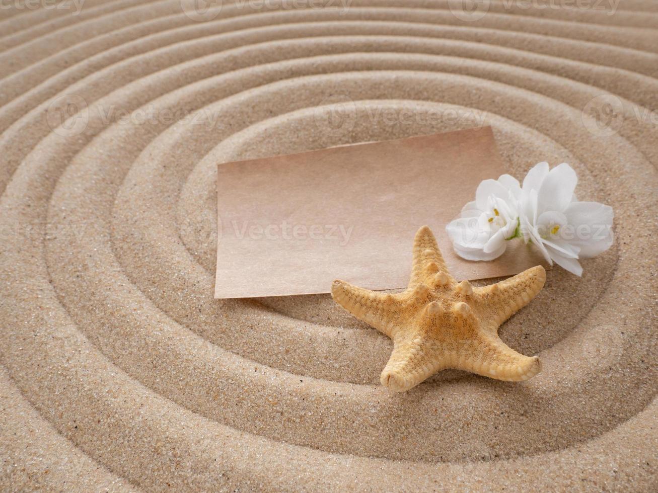 Brief im das Sand. Papier mit Blume und Seestern auf das Sand im das gestalten von ein Spiral. das Konzept von ein Strand Urlaub foto