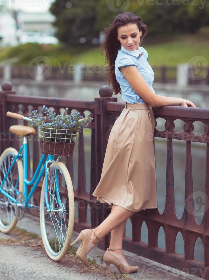 junge schöne, elegant gekleidete Frau mit Fahrrad. Schönheit, Mode und Lifestyle foto