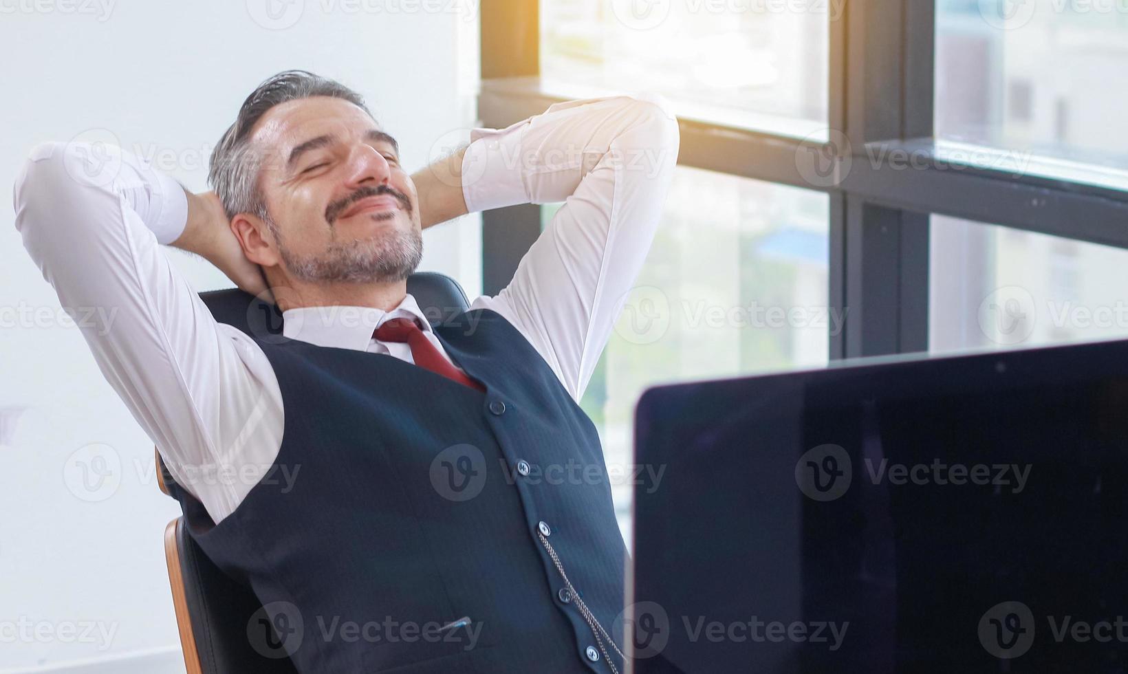 glücklicher junger Geschäftsmann, der an einem modernen Büro ruht foto