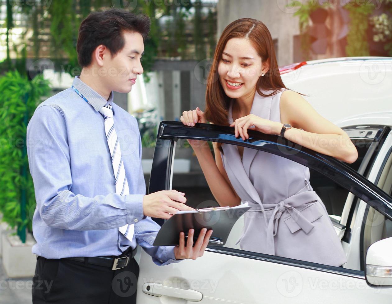 Verkäufer und Käufer im Autohaus mit Kaufvertrag foto
