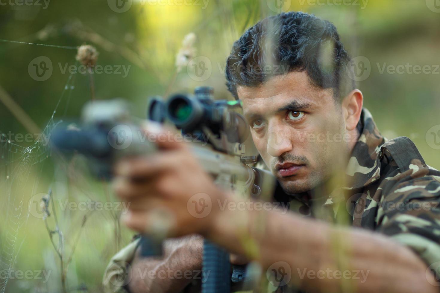 Mann von arabisch Staatsangehörigkeit im tarnen mit ein Gewehr Zielen beim ein Ziel foto