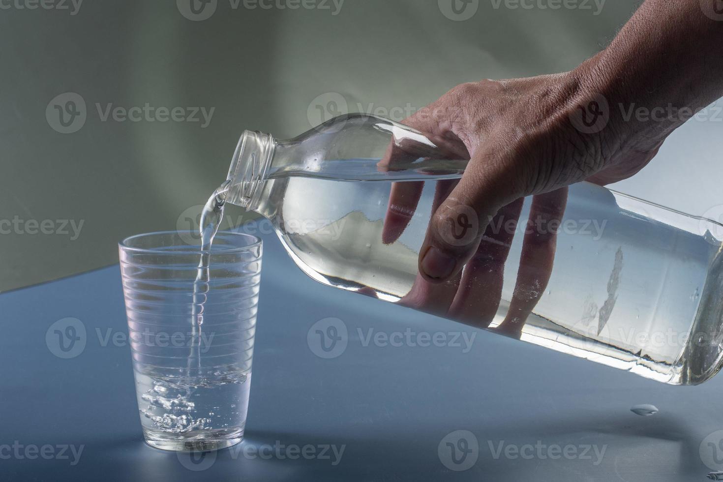 Detail von Person Füllung Glas von Wasser. Flüssigkeitszufuhr Konzept foto