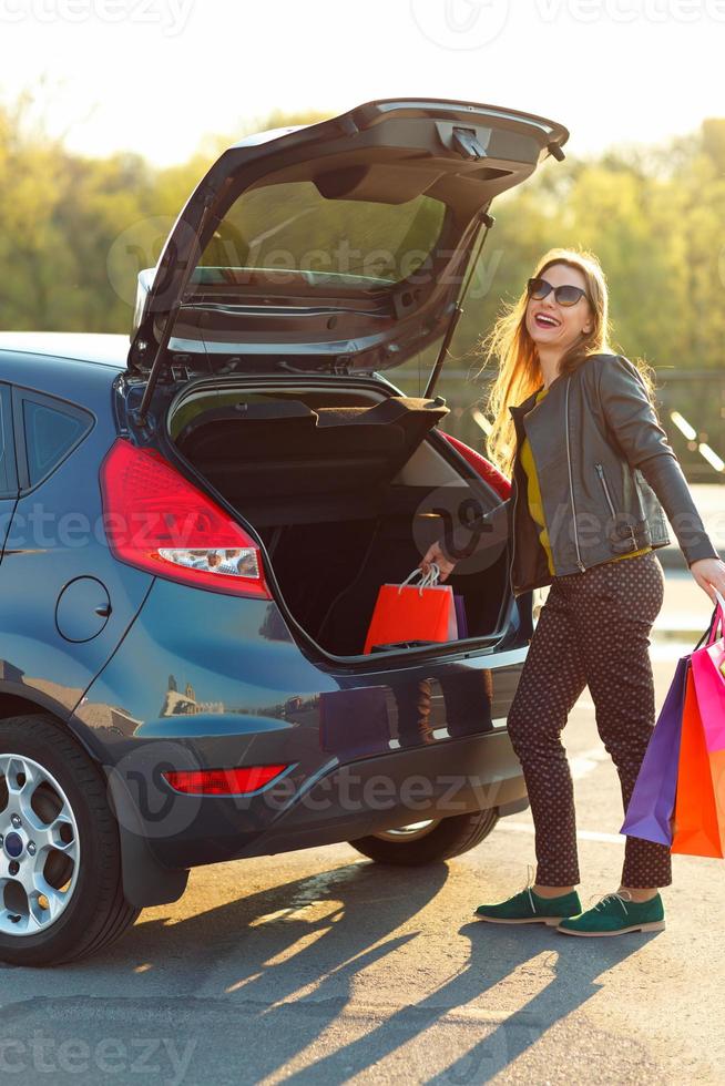 Frau Putten ihr Einkaufen Taschen in das Auto Kofferraum foto