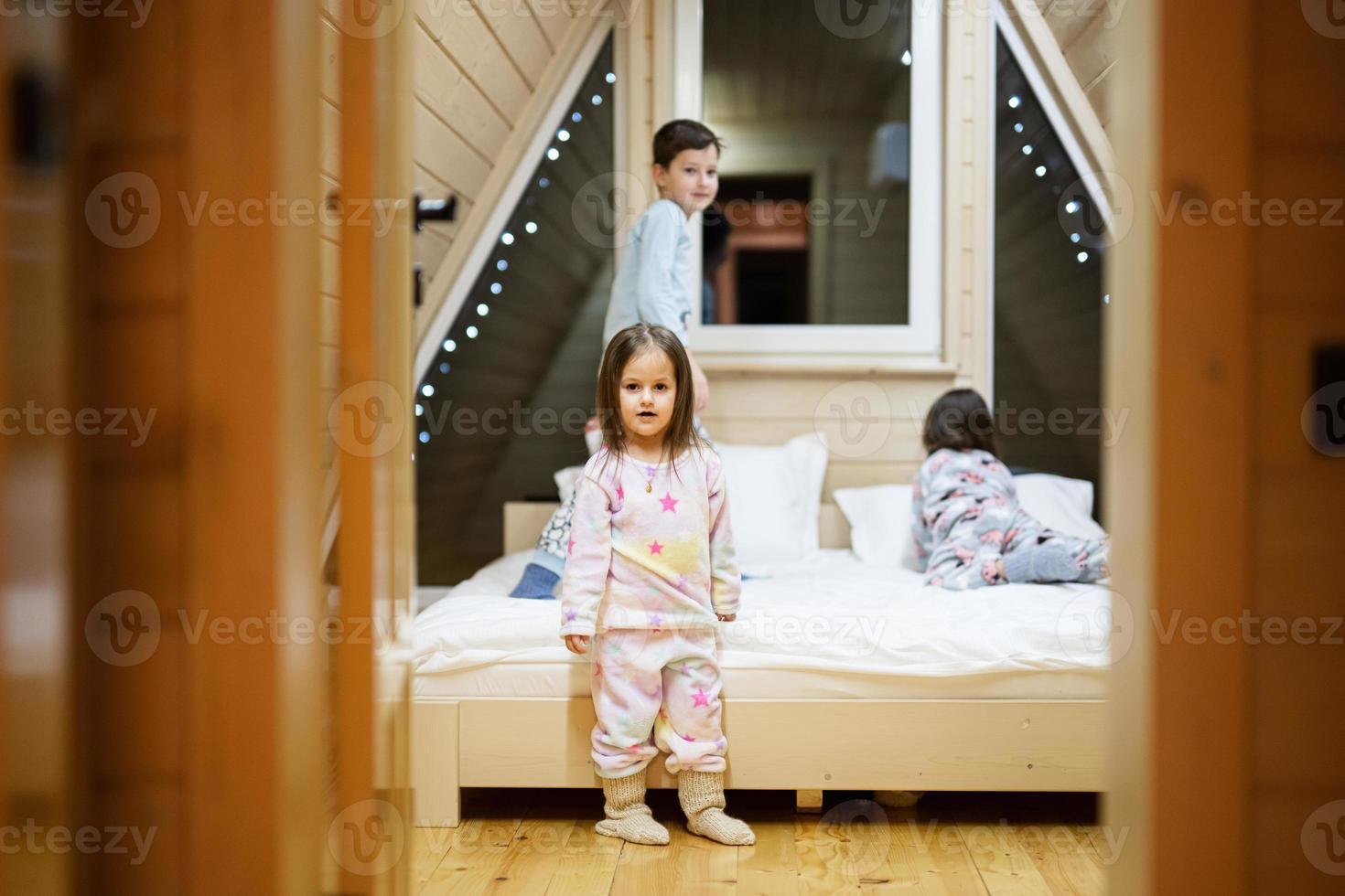 Kinder im Sanft warm Pyjama spielen beim hölzern Kabine heim. Konzept von Kindheit, Freizeit Aktivität, Glück. Bruder und Schwestern haben Spaß und spielen zusammen. foto